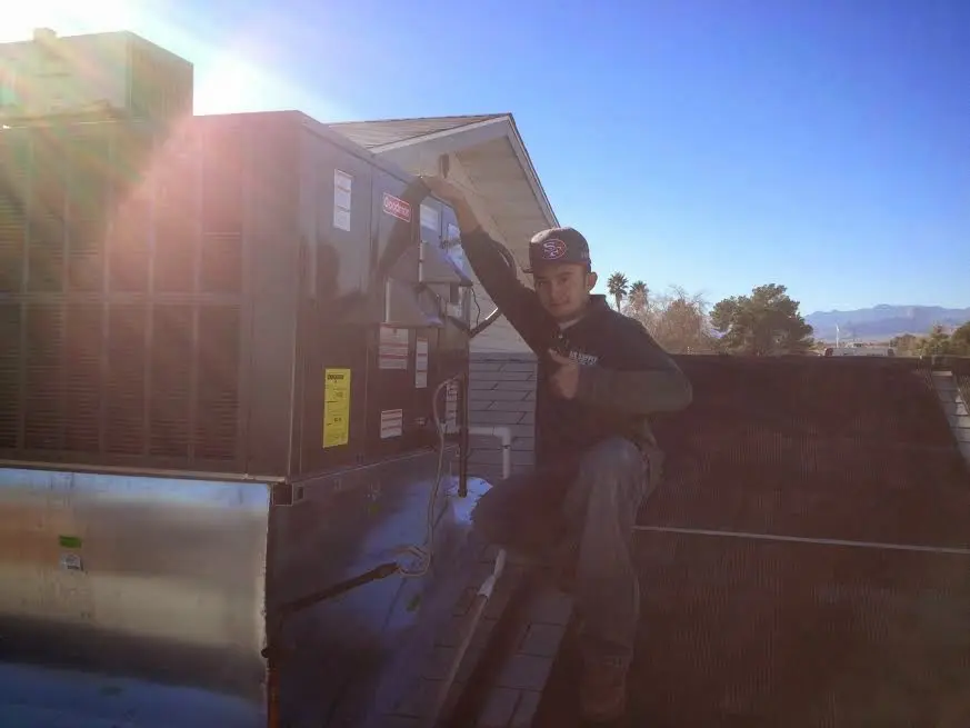 HVAC technician performing AC Tune-Up on a rooftop unit in Woodburn